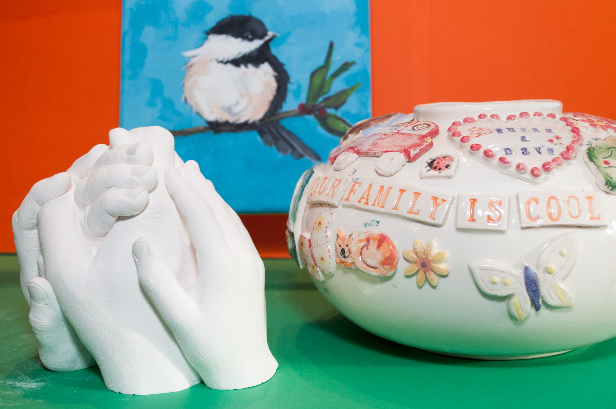 a hand cast, a painting of a bird and a hand made vase decorated with flowers and butterflies