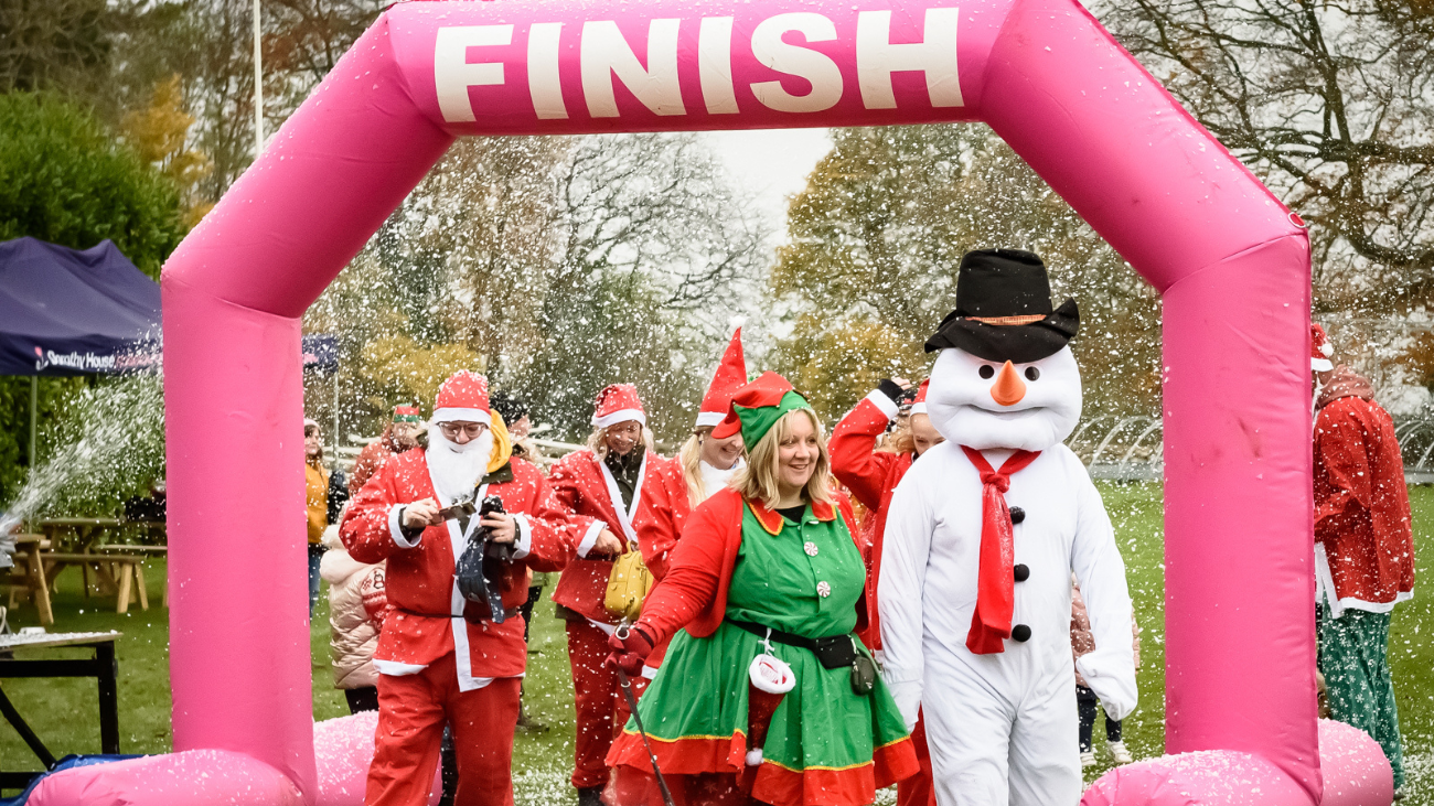Supporters dressed as Santas and a snowman crossing the finish line