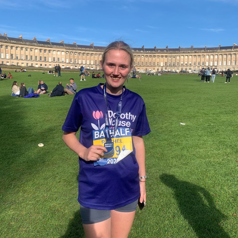 Young Bath Half Marathon runner holding medal in the city of Bath