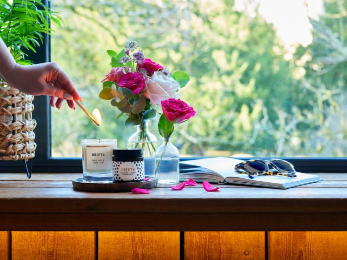 Lighting candle on windowsill surrounds by flower petals