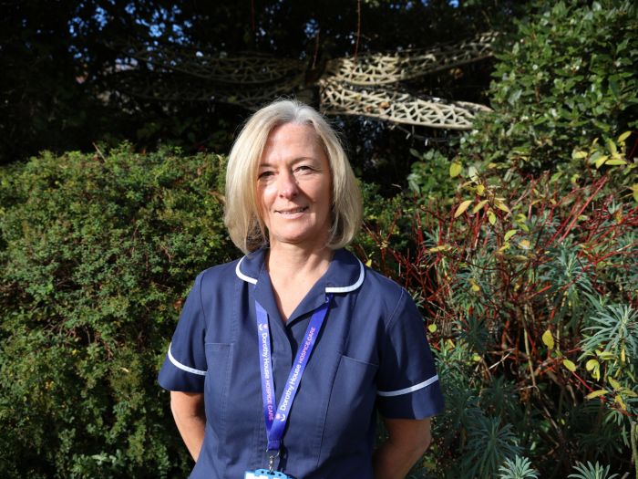 Nurse standing with hands behind back smiling - honouring caregivers