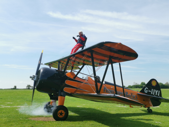 Dorothy House Wingwalker, Freda, strapped to an orange bi-plane
