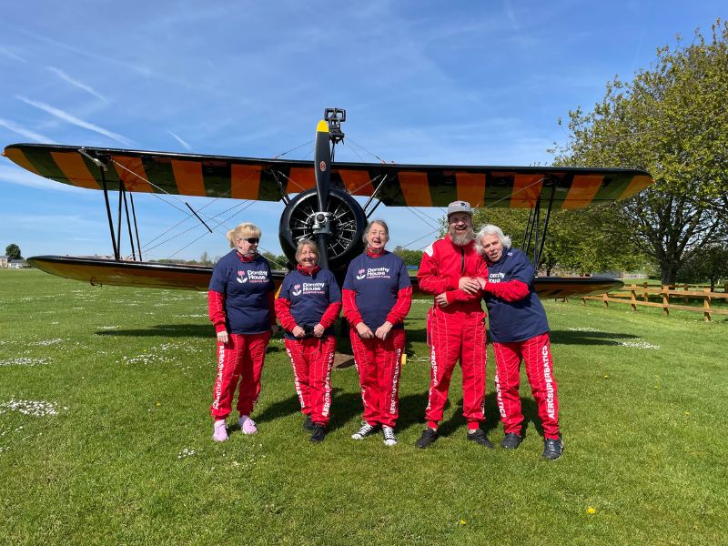 Wingwalkers in front of biplane wearing red jumpsuits