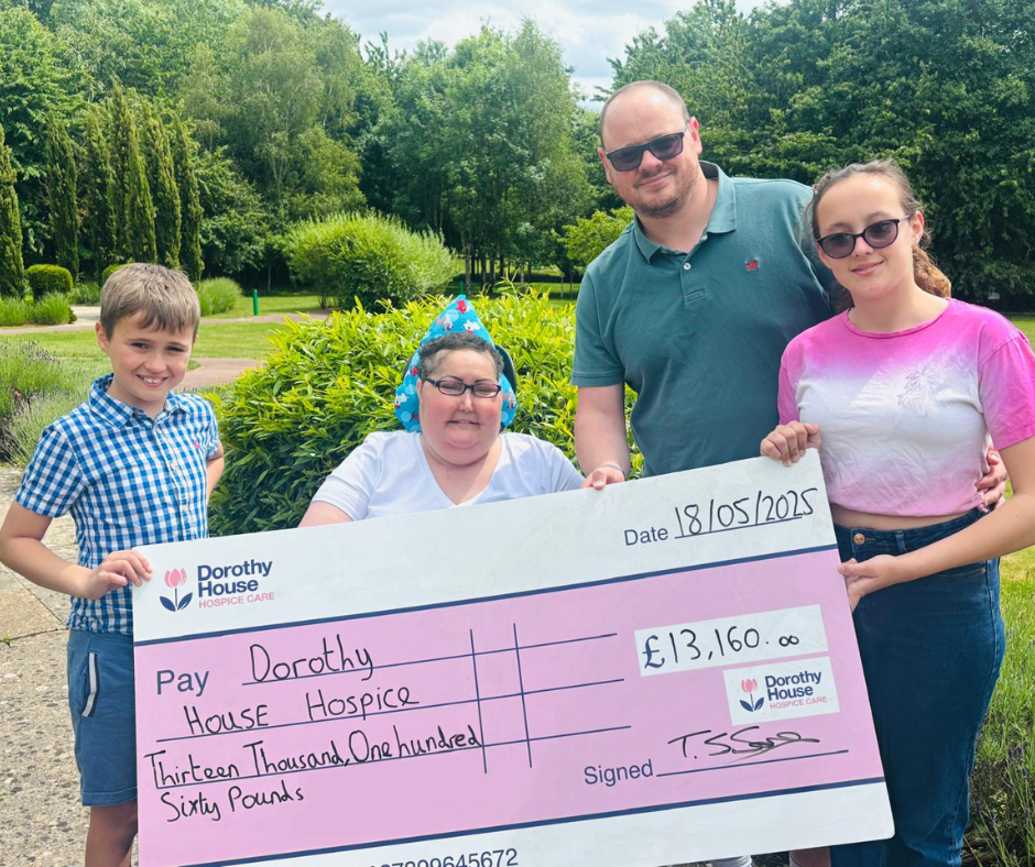 Family of four (two children, two adults) holding up a big cheque