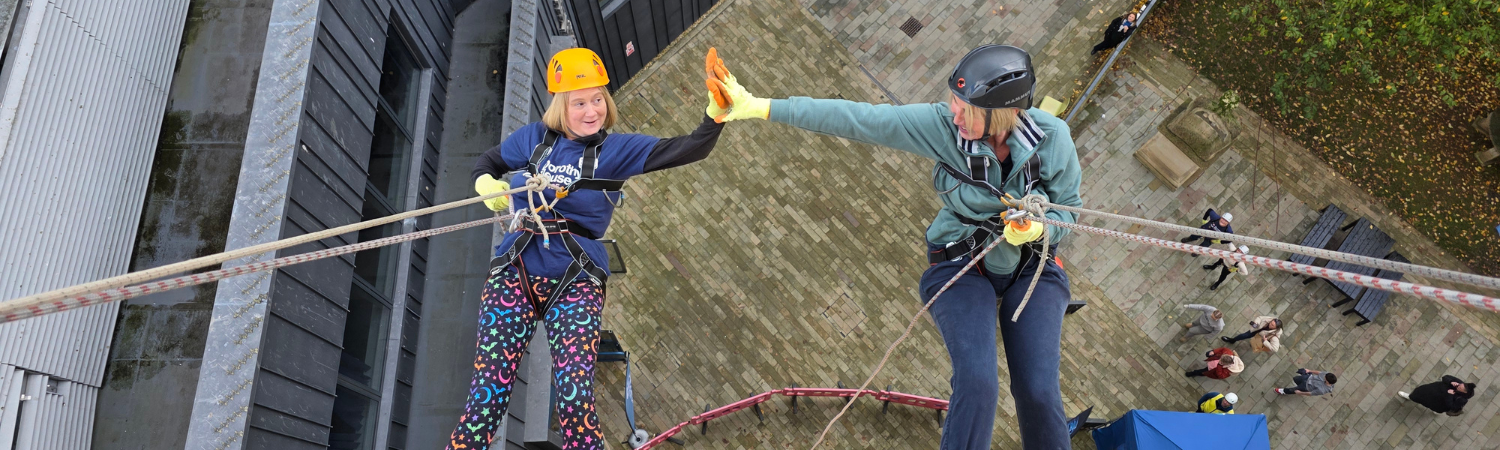 Two women high diving whilst abseiling down a building