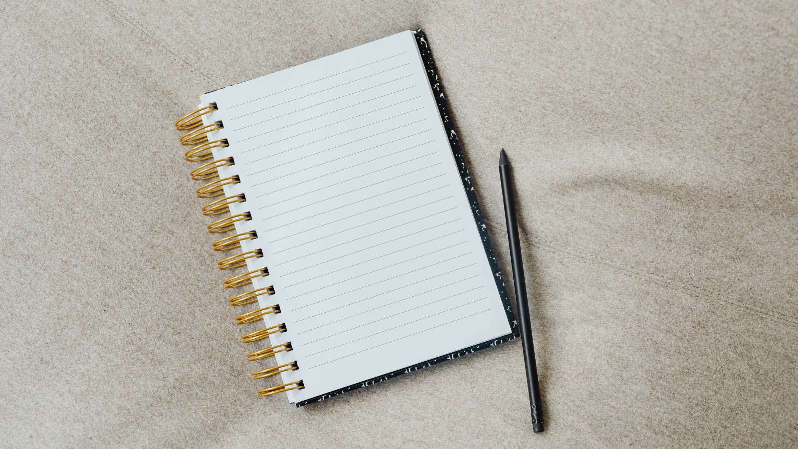 Notepad and pencil against a beige material